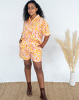 dark curly hired girl wearing 70's inspired swirl pattern linen clothing. beachy shirt and shorts set crafted ethically and sustainably.